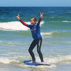 young surfer giving peace sign while riding a wave